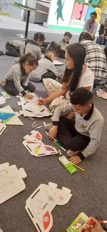 Children colouring cardboard figures on the floor